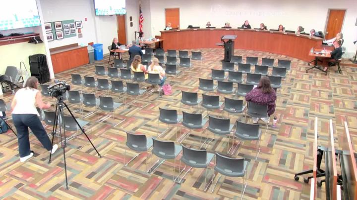 The School Board room with row of chairs facing the dais filled with board members.